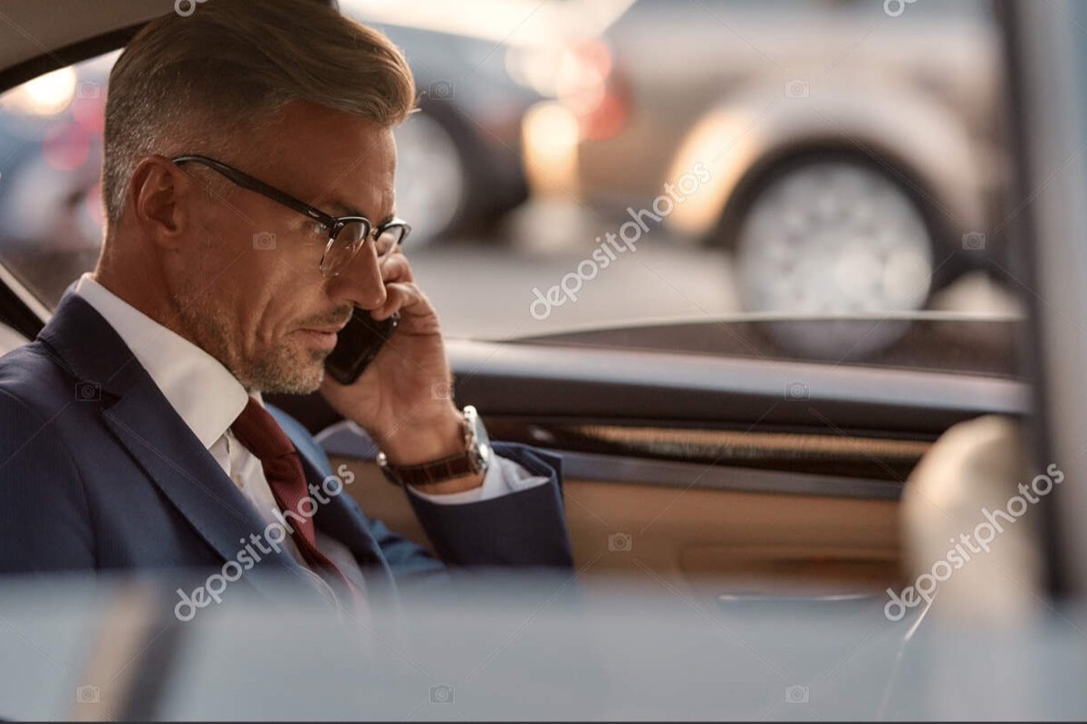 Klient v obleku telefonuje na zadnom sedadle luxusného vozidla